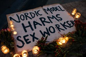 Candles around a sign, sign reads 'Nordic model harms sex workers'