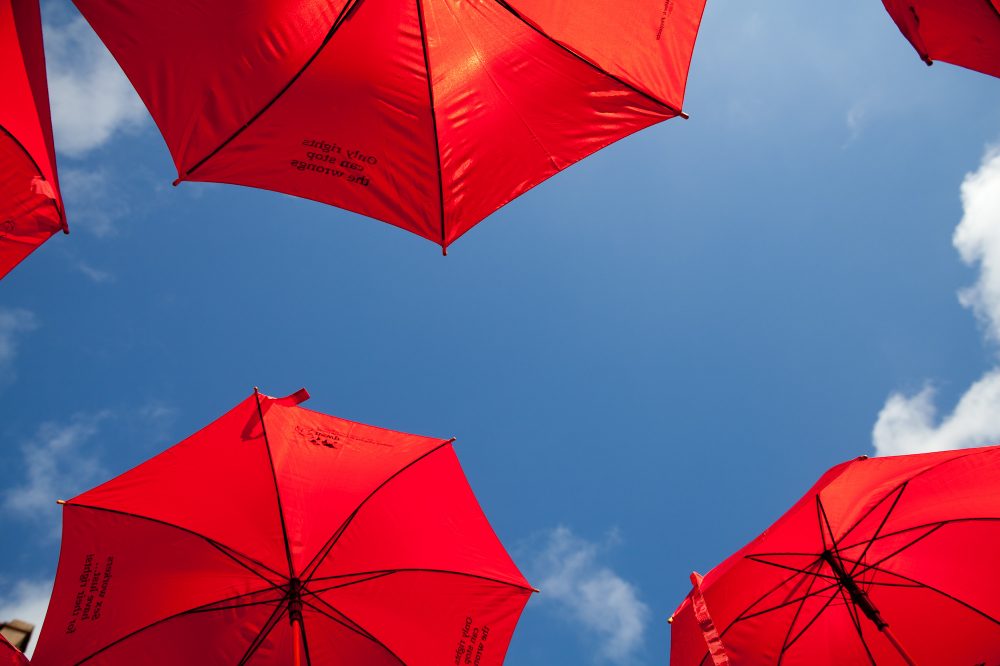 an image of a blue sky framed by the undersides of red umbrellas